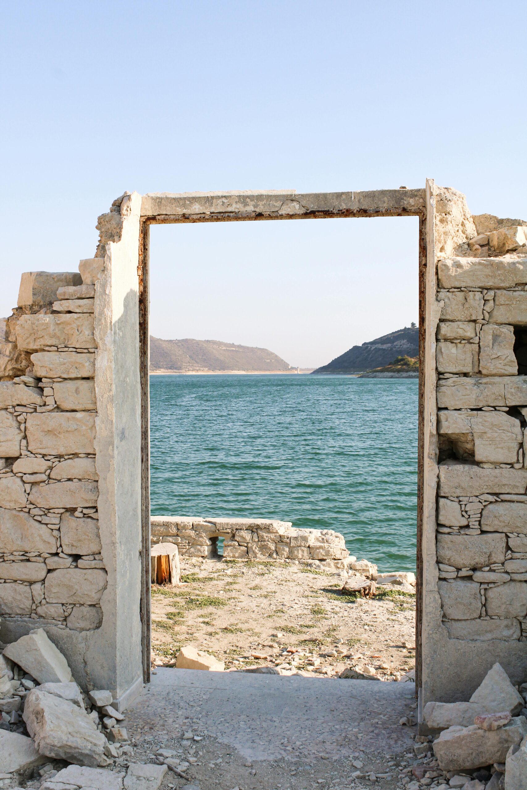 Ancient stone doorway framing a scenic view of Cyprus coastline with clear sky and sea.