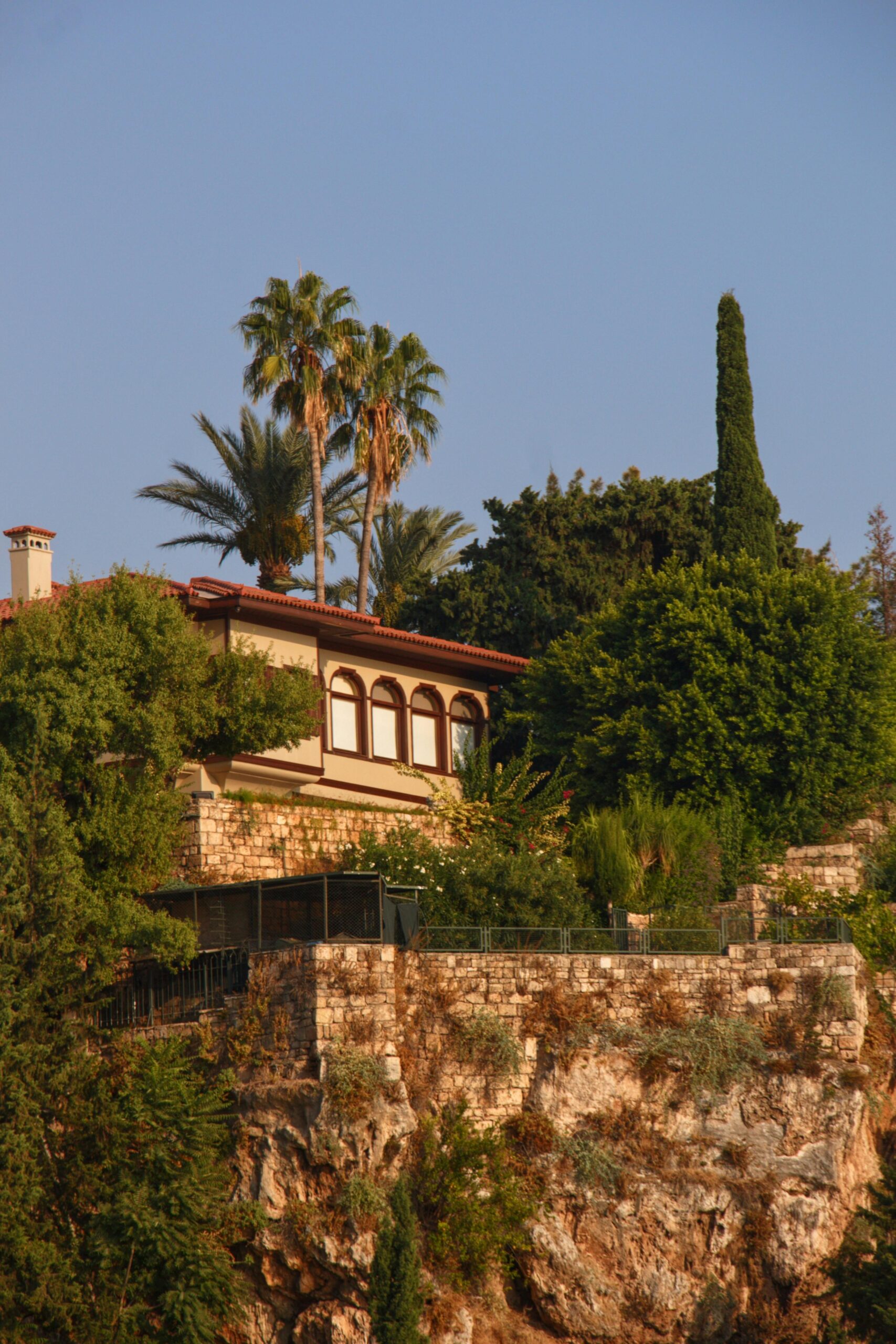 Charming Mediterranean villa nestled on cliffs amid lush trees in Antalya, Turkey.